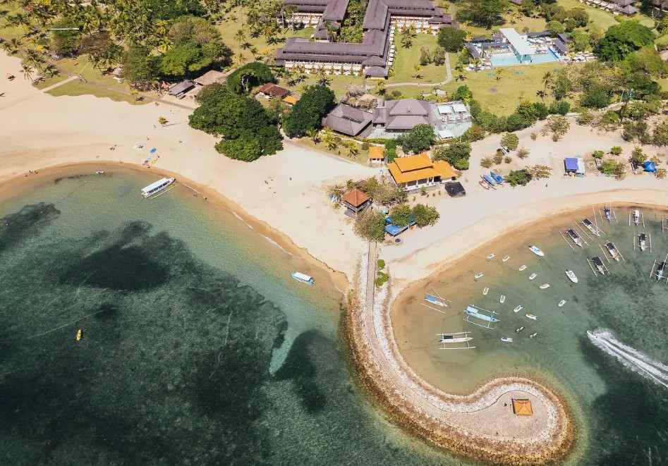 Vista aérea do Club Med Bali com piscina, praia e quebra-mar em gancho com pavilhão no mar