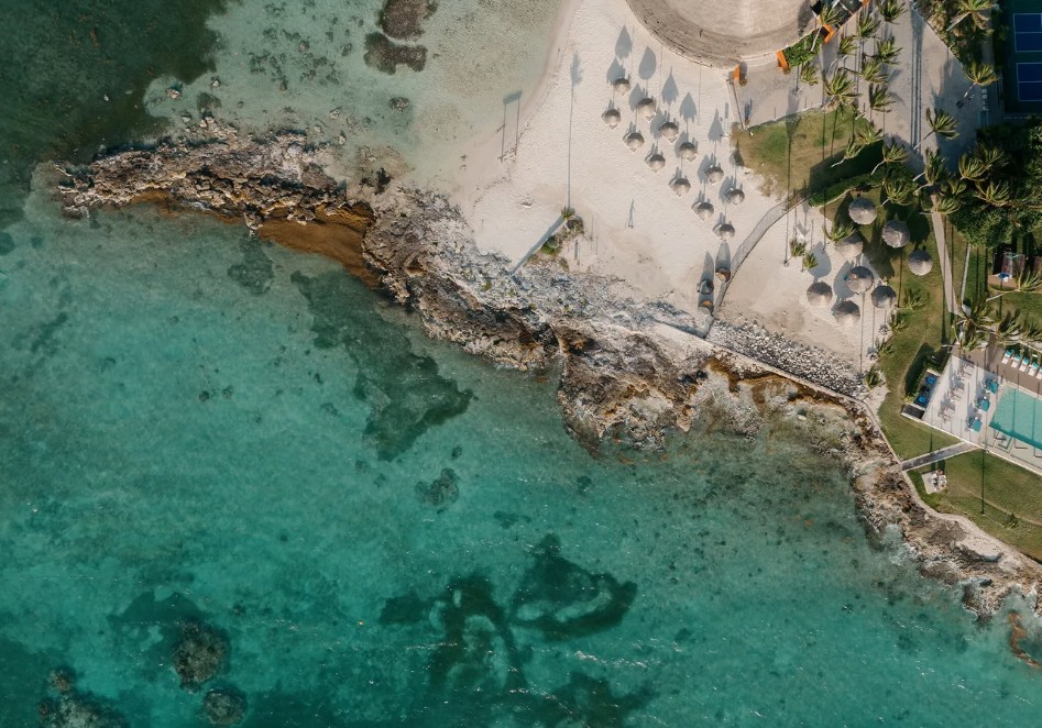 Vista aérea da orla rochosa do Club Med Cancún Yucatán, praia, palapas e piscina no Caribe