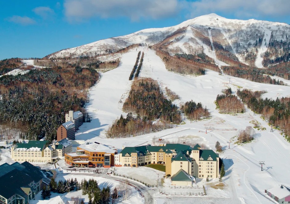 Village Club Med em Hokkaido na base da montanha nevada, com pistas e teleférico sob céu azul