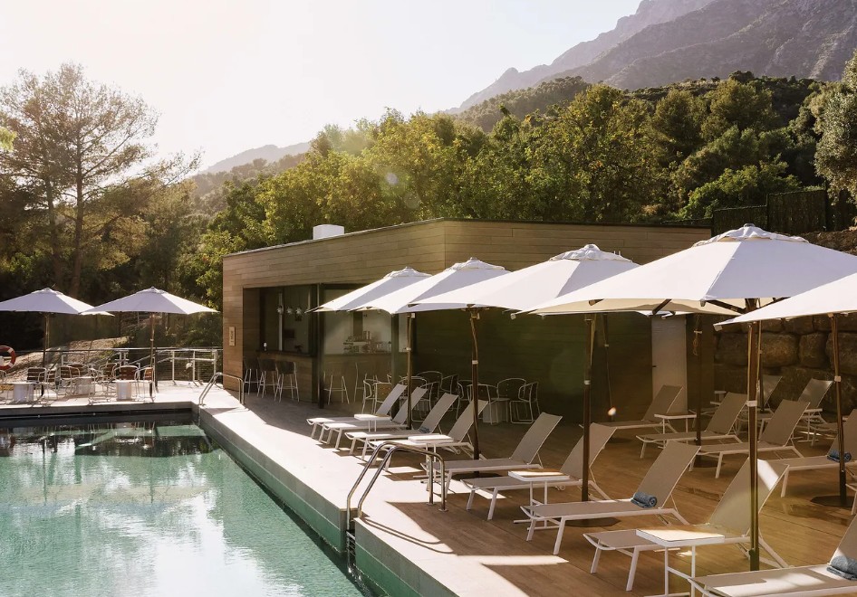 Deck de madeira e piscina do Club Med Magna Marbella, com bar e montanhas da Costa do Sol ao fundo