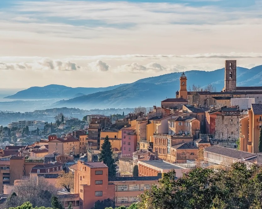 Telhados de terracota e torres de Opio-en-Provence, com vale enevoado e o Mediterrâneo ao fundo