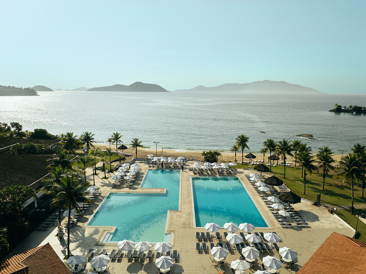 Piscinas do Club Med Rio das Pedras com espreguiçadeiras e palmeiras, praia e ilhas ao fundo