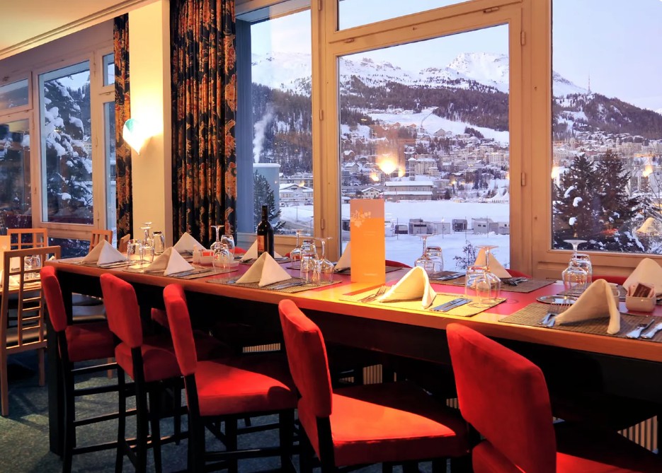 Restaurante do Club Med Saint-Moritz com mesa posta e vista para o lago congelado e as montanhas